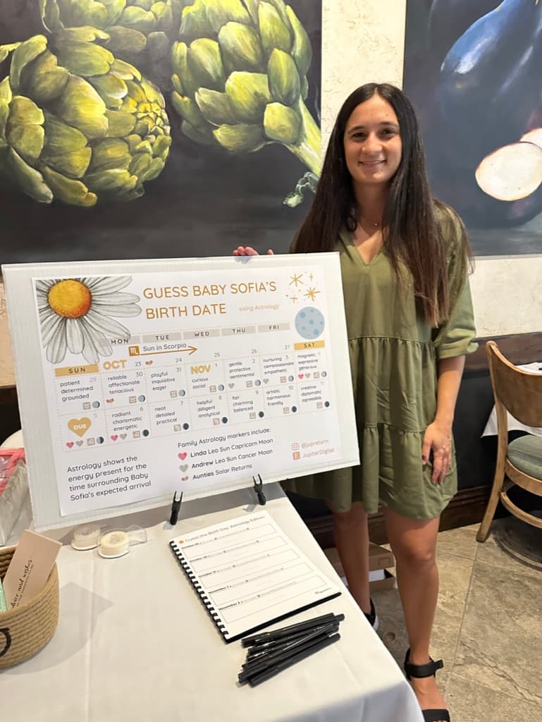Christina presenting a baby shower astrological calendar at a party